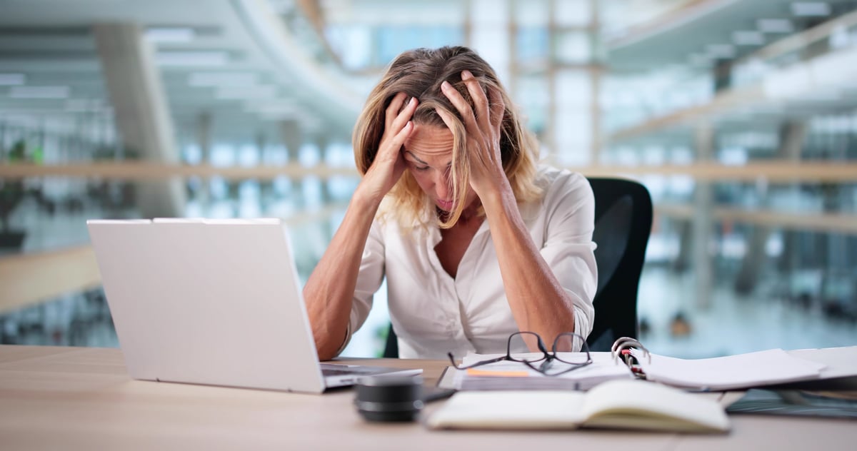 Frustrated woman working at computer desk showing stress and anxiety