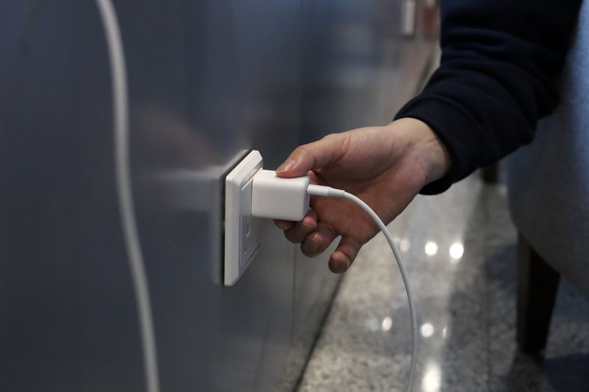 Hand plugging charger into wall socket